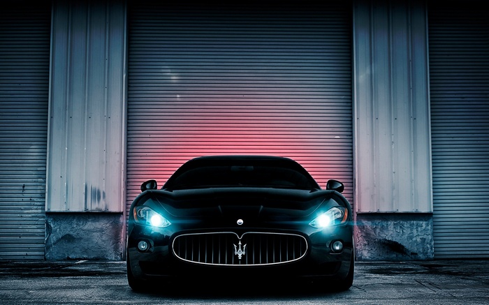 Black Maserati parked in front of a garage door