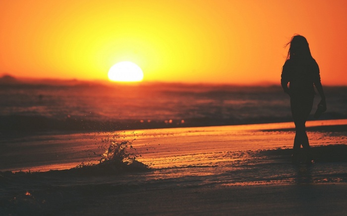Woman walking on beach at sunset