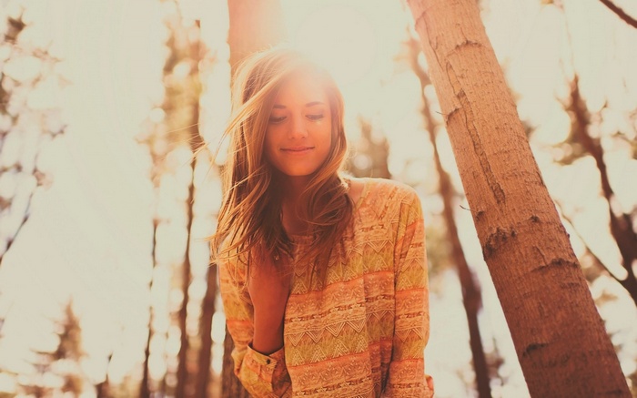 Woman smiling in sunlight among trees