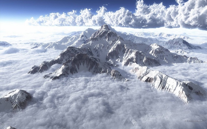 Snow-capped mountains above clouds under a blue sky