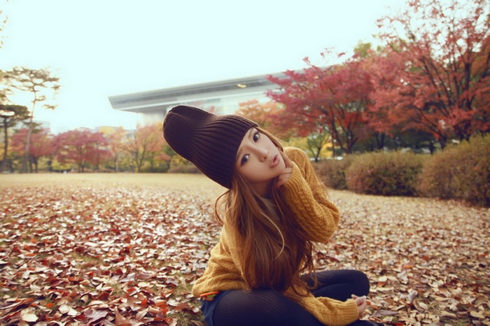 Asian woman wearing a hat and sweater in autumn park
