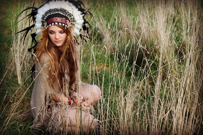 Woman in headdress sitting in tall grass