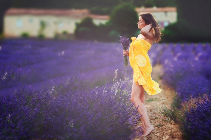 Woman in yellow dress holding lavender in a field