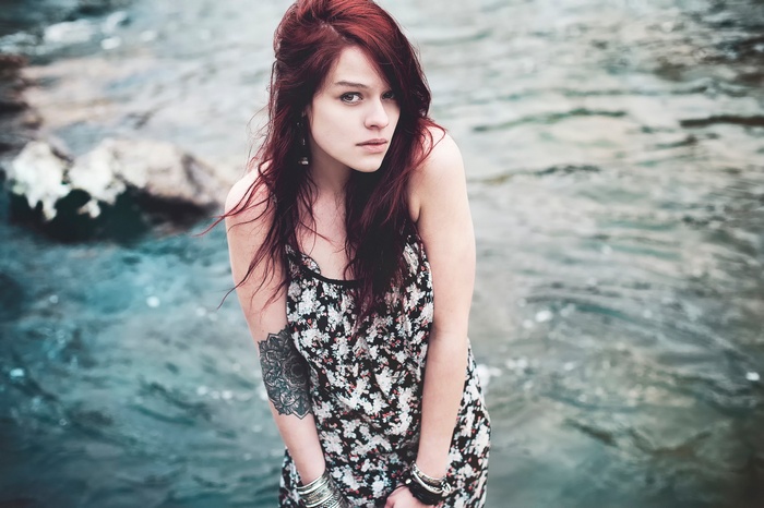 Woman with red hair and tattoo by the water