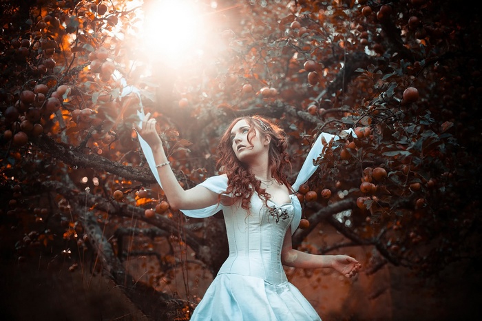 Woman in a white corset dress in an apple orchard
