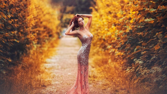 Woman in a sparkling dress in an autumn forest