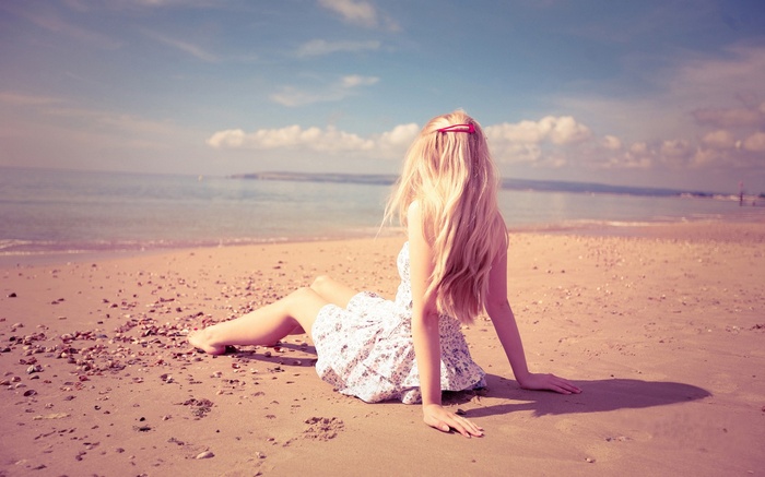 Woman with blonde hair sitting on a beach