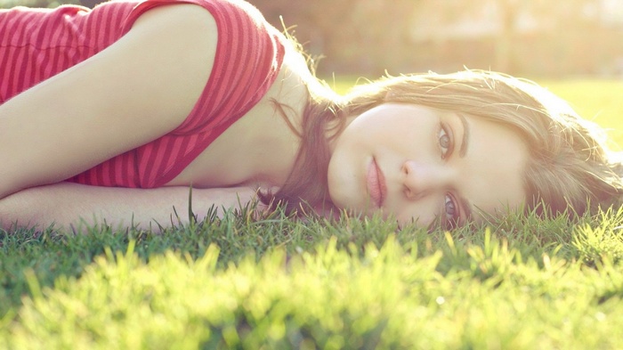 Woman lying in grass in sunlight