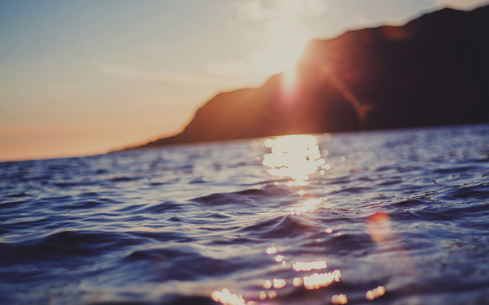 Sunlight reflecting on the sea near a rocky shore