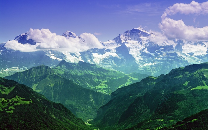 Snow-capped mountains with clouds and green valleys