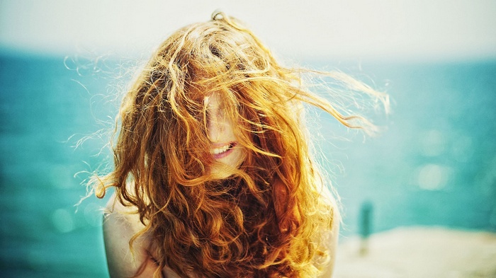 Redhead woman with curly hair in the wind