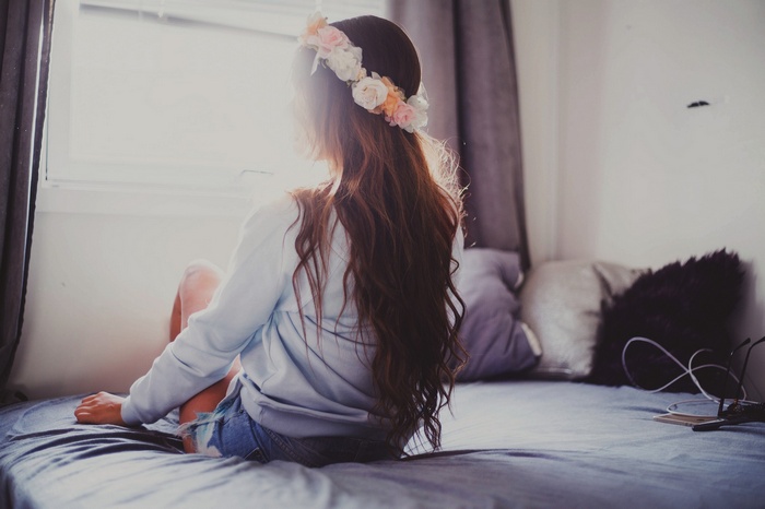 Woman with flower crown sitting on a bed