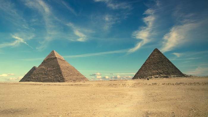 The Pyramids of Giza in Egypt under a blue sky