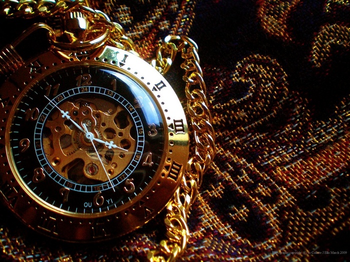 Gold pocket watch with chain on patterned fabric