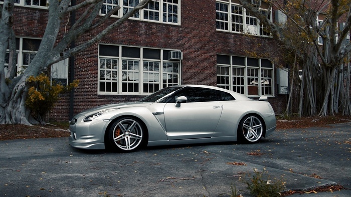 Silver Nissan GT-R parked in front of a brick building