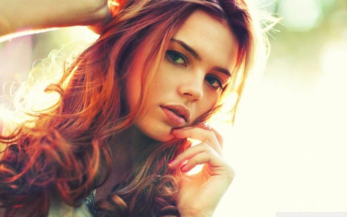 Redhead woman with curly hair looking at viewer