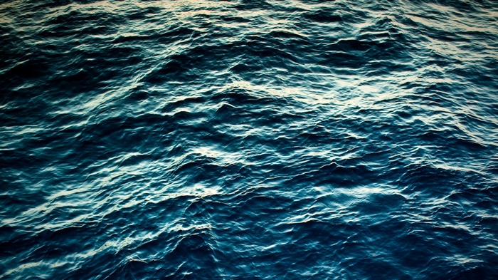 Dark blue ocean waves with sunlight reflections