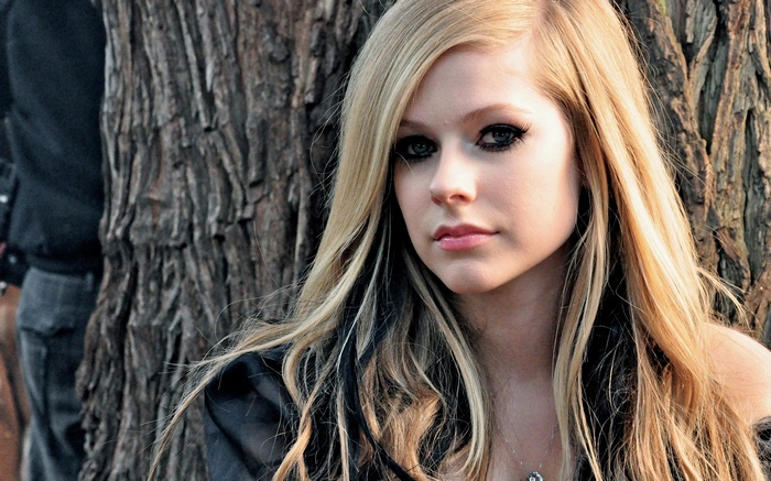 Avril Lavigne posing by a tree