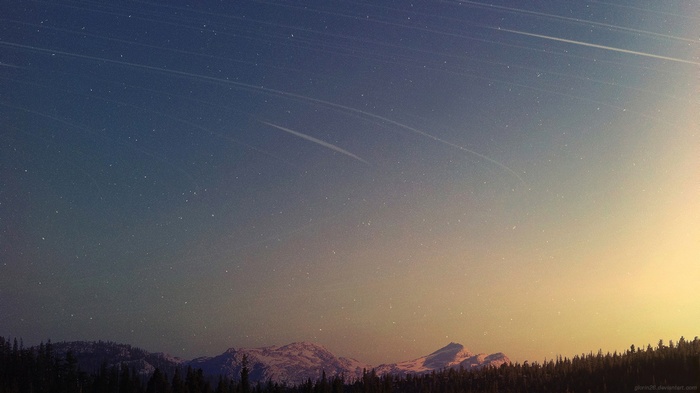 Starry night sky over snow-capped mountains and forest