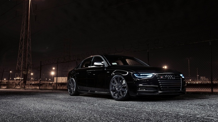 Black Audi S4 parked at night near a fence