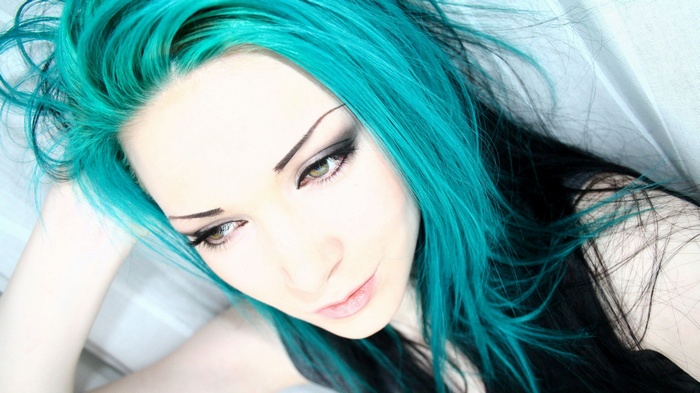 Woman with bright teal dyed hair and dark makeup