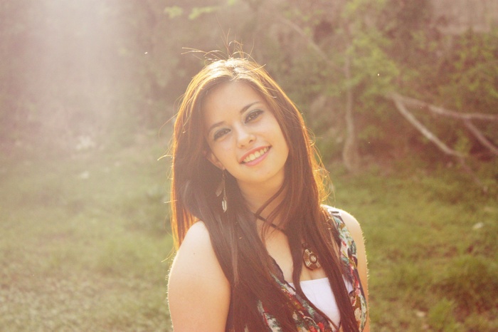 Young woman with long brown hair smiling outdoors
