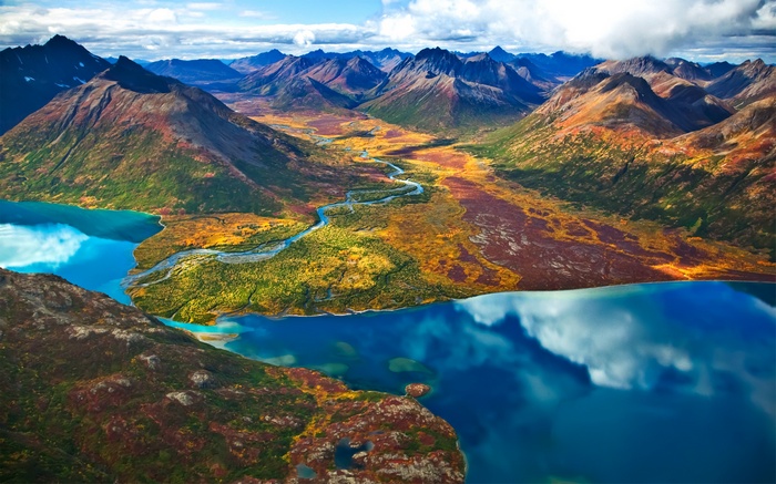 Aerial view of a winding river flowing through mountains and lakes