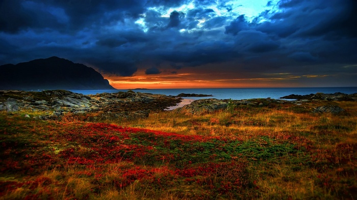 Dramatic sunset over a rocky coastline with stormy clouds