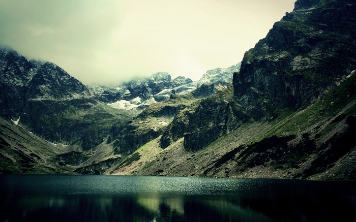 Misty mountains reflected in a dark lake