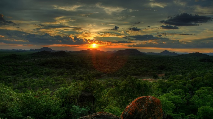 Sunset over a vast green landscape with mountains