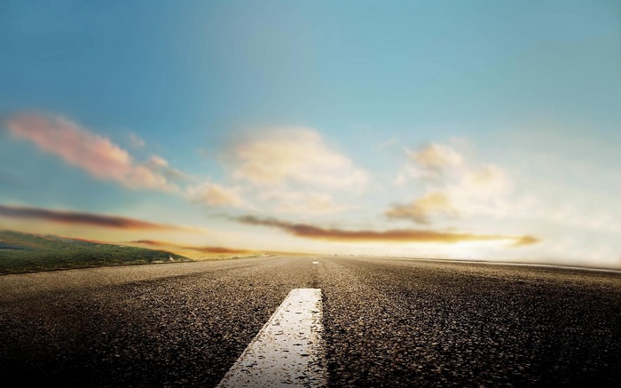 Road stretching towards the horizon under a cloudy sky