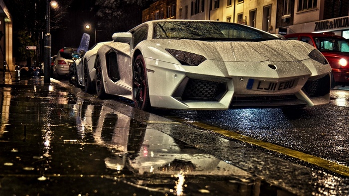 White Lamborghini Aventador parked on wet street at night