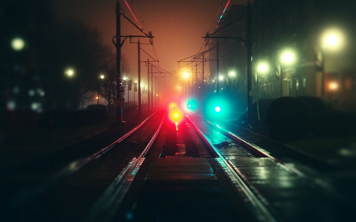 Train tracks at night with red and green lights