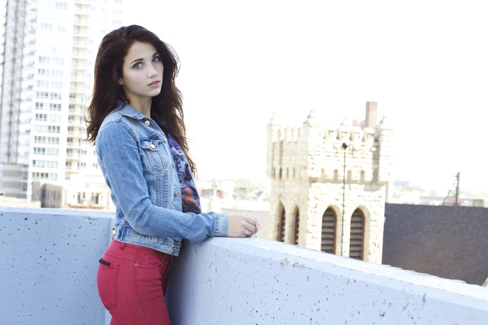 Emily Rudd on a rooftop with city buildings