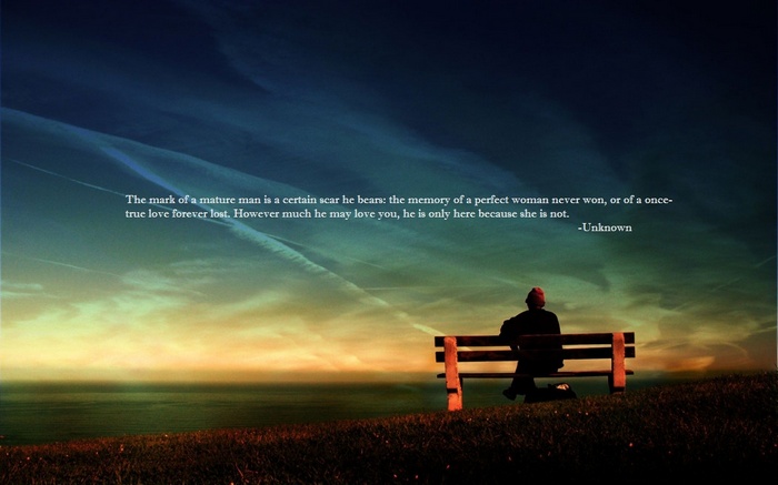 Man sitting on a bench overlooking the ocean at sunset