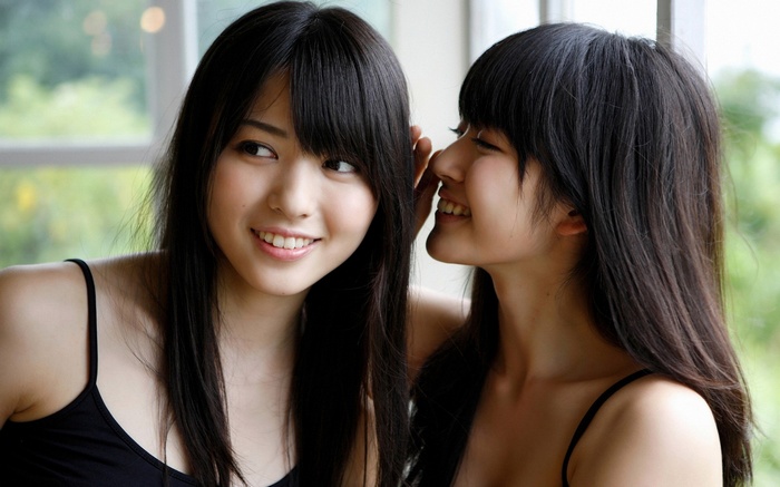 Two Asian women whispering secrets