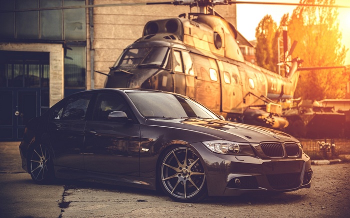 BMW E90 sedan parked in front of a helicopter