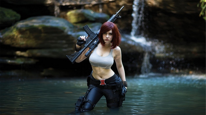 Black Widow cosplay with a rifle in a waterfall