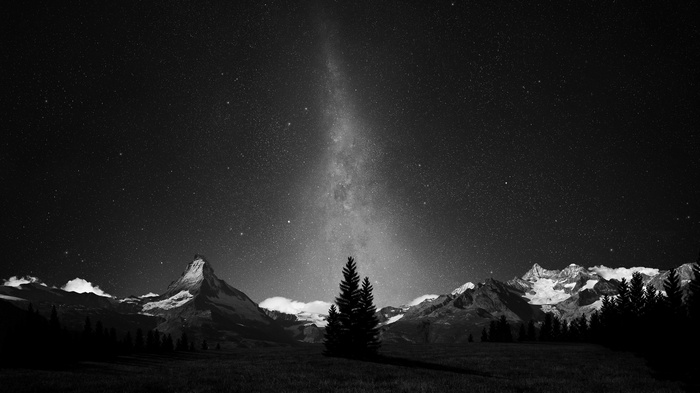 Monochrome Milky Way over snow-capped mountains and forest