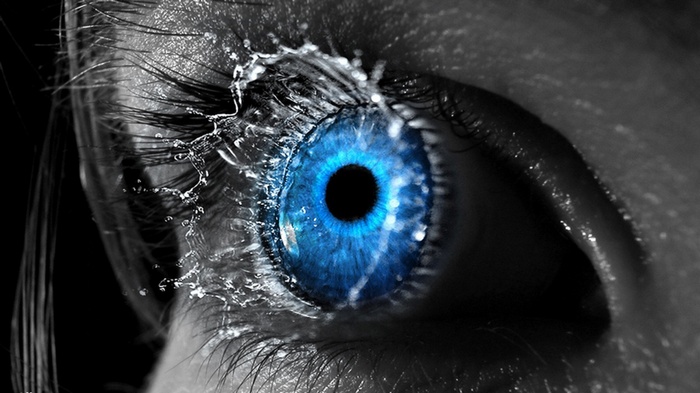 Close-up of a blue eye with water splashing on it