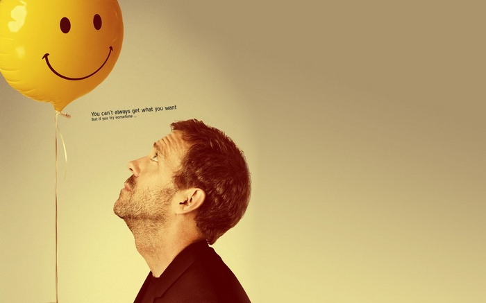 Hugh Laurie looks up at a smiley face balloon