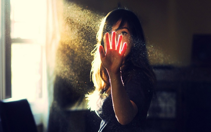 Woman holding hand up in dusty sunlight
