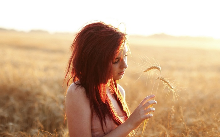 Redhead woman in a wheat field at sunset