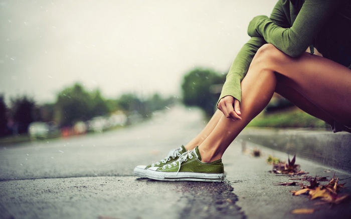 Woman in Converse sitting on pavement in rain