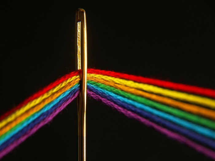 Needle and rainbow yarn on black background