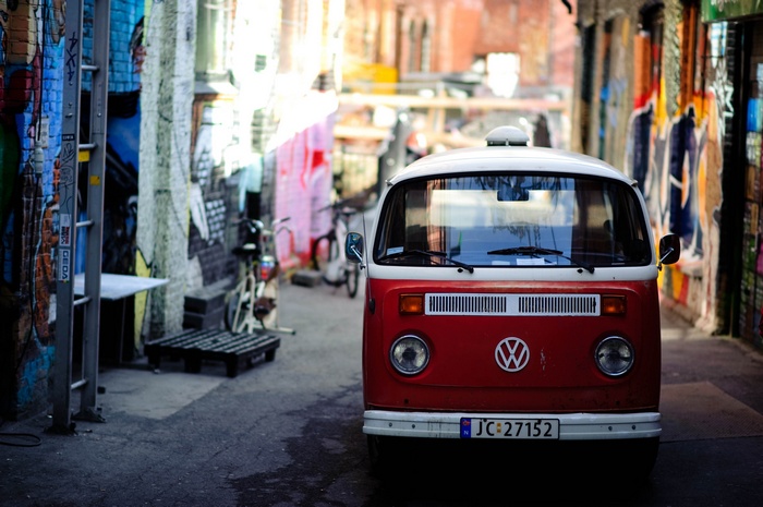 Red Volkswagen Combi van parked in a graffiti alley