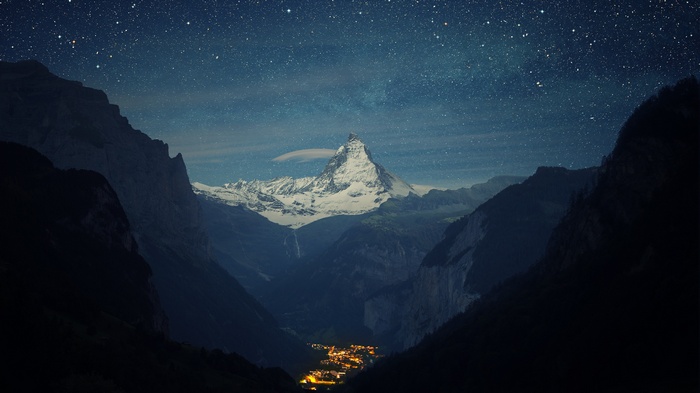 Matterhorn mountain at night with stars and a village