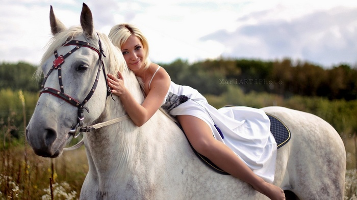 Woman in white dress lying on a white horse