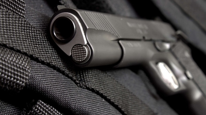 Close-up of a M1911 pistol on a black textured surface