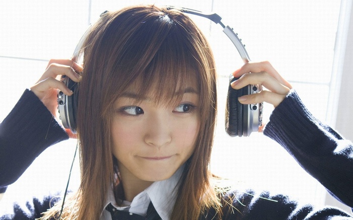 Asian woman wearing headphones and a sweater